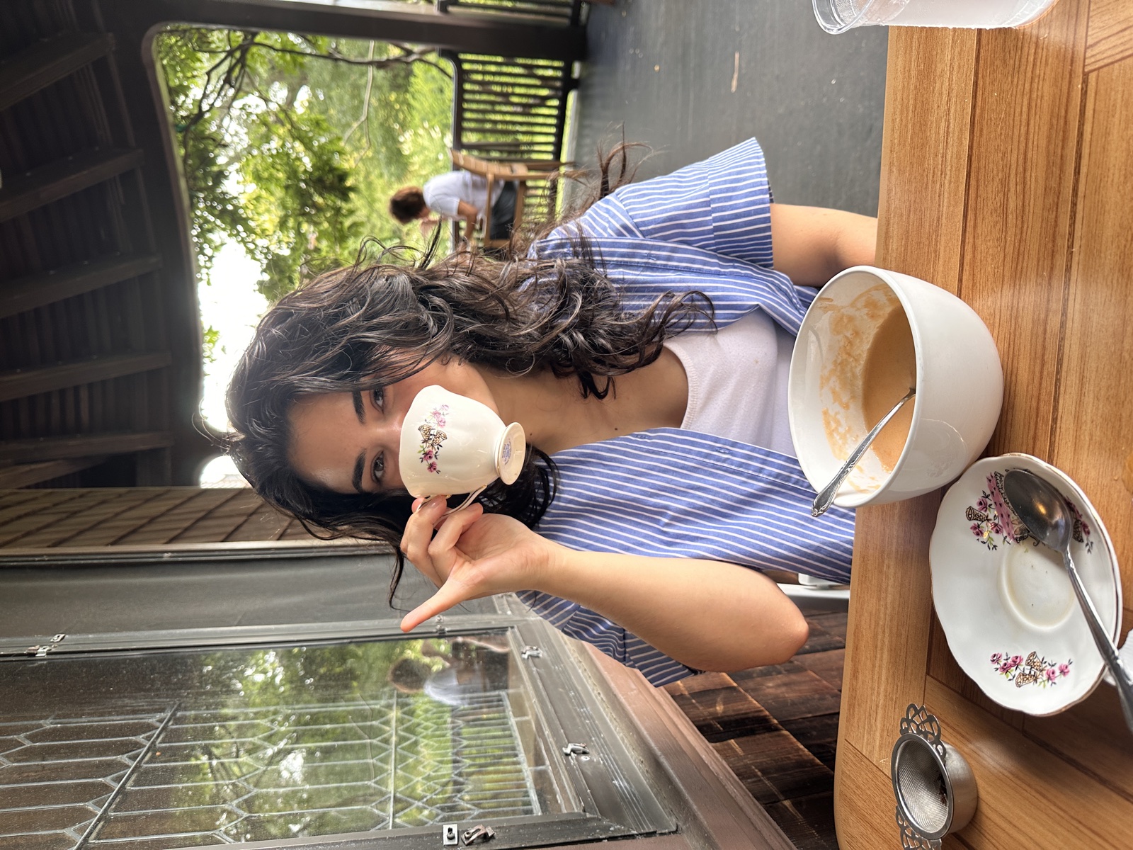 Genevieve drinking tea from a floral teacup on a porch